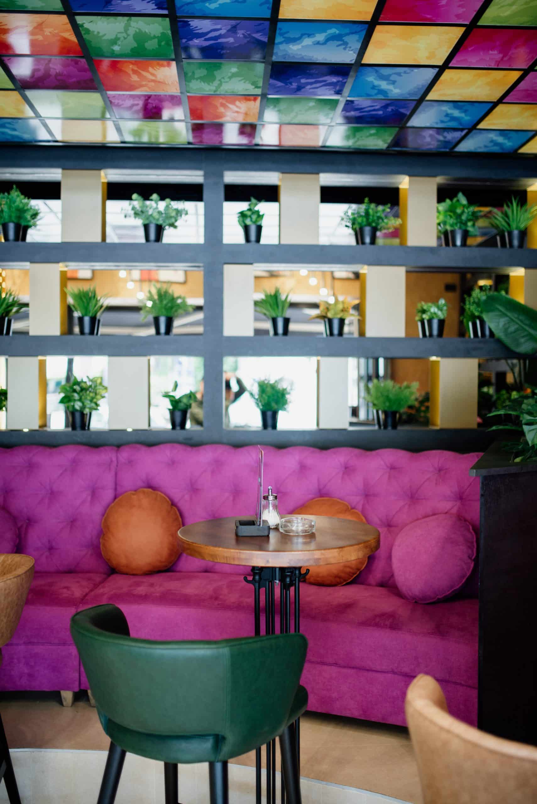 Colorful cafe seating area with a magenta banquette and living plant wall