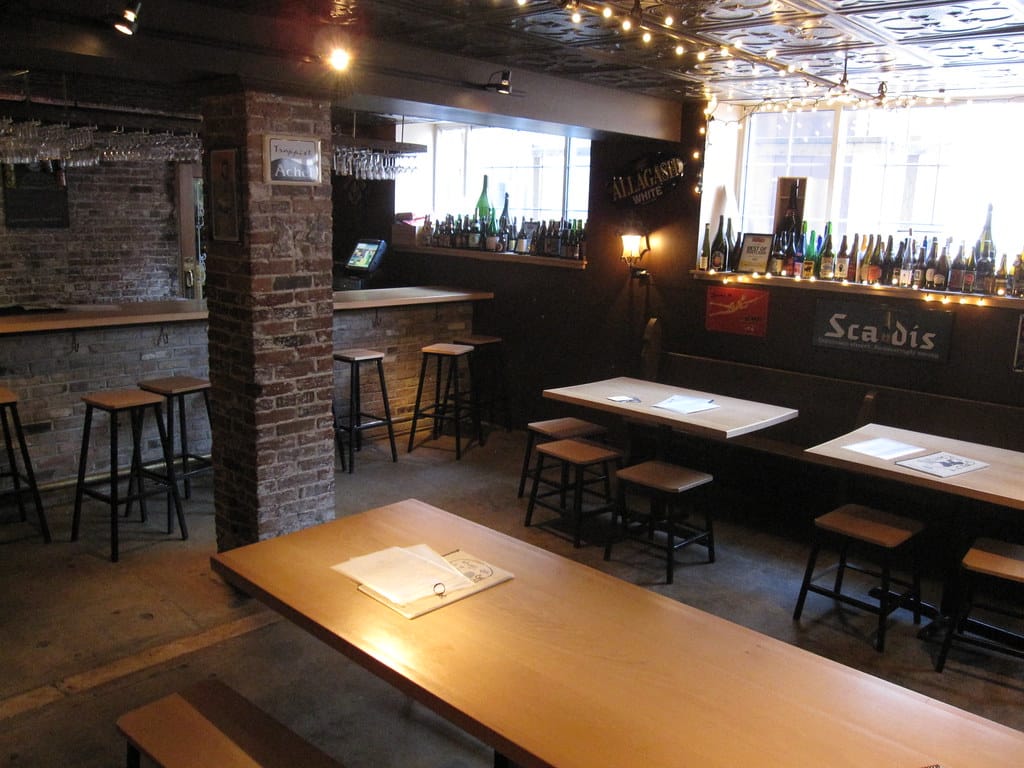 Long communal wooden tables with stools in a cafe, encouraging shared seating