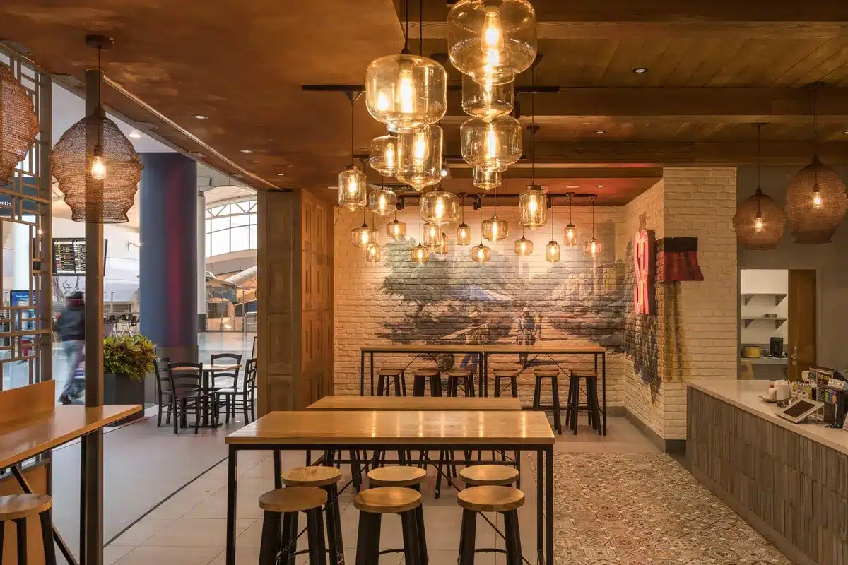Restaurant Interior Design: Ideas From Real NZ Projects 2 Silk Road restaurant at Auckland Airport with clusters of glass pendant lights, timber tables and a street-scene mural