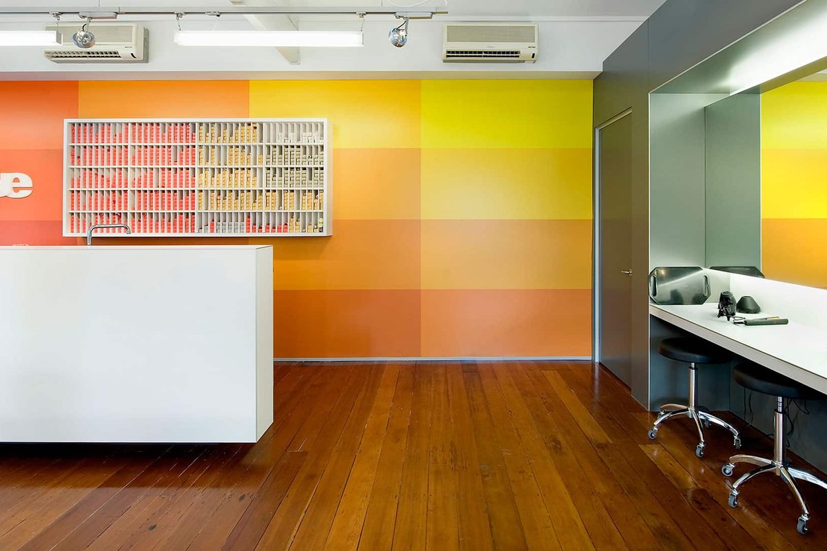 Salon Interior Design: Layout Ideas for Hair Salons 1 Salon reception counter in front of a colour swatch display and a wall graded from orange to yellow